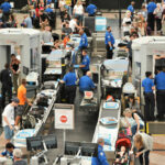 Airport security checkpoint with passengers and staff busy