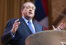 Man in suit speaking at podium on stage