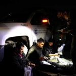 Officials interacting with seated individuals at nighttime outdoors