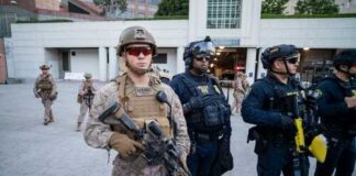 Military and police personnel in tactical gear standing in an urban area