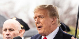 Two men speaking at an outdoor event in suits
