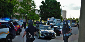Police officers in riot gear managing a scene with emergency vehicles