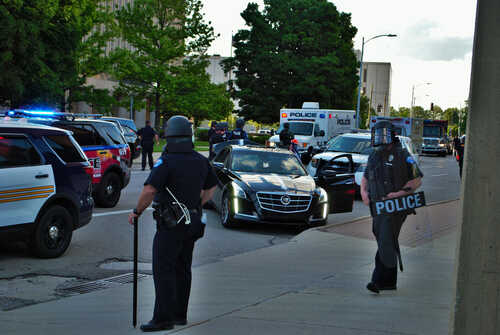 Police officers in riot gear managing a scene with emergency vehicles