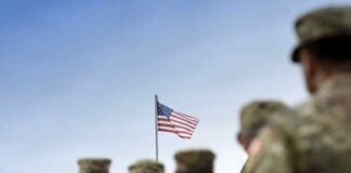 Soldiers standing in formation with an American flag in the background