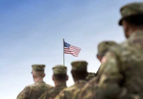 Soldiers standing in formation with an American flag in the background