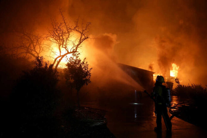Firefighter battling blaze at night with hose spray