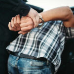Person in handcuffs being detained by police officer