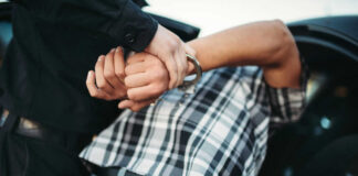 Person in handcuffs being detained by police officer