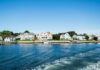 Waterfront houses along a sunny coastline with boats