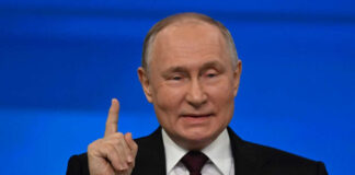 Man in suit gestures with raised index finger