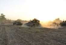 Military tanks moving through a dusty field at sunset