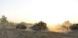 Military tanks moving through a dusty field at sunset